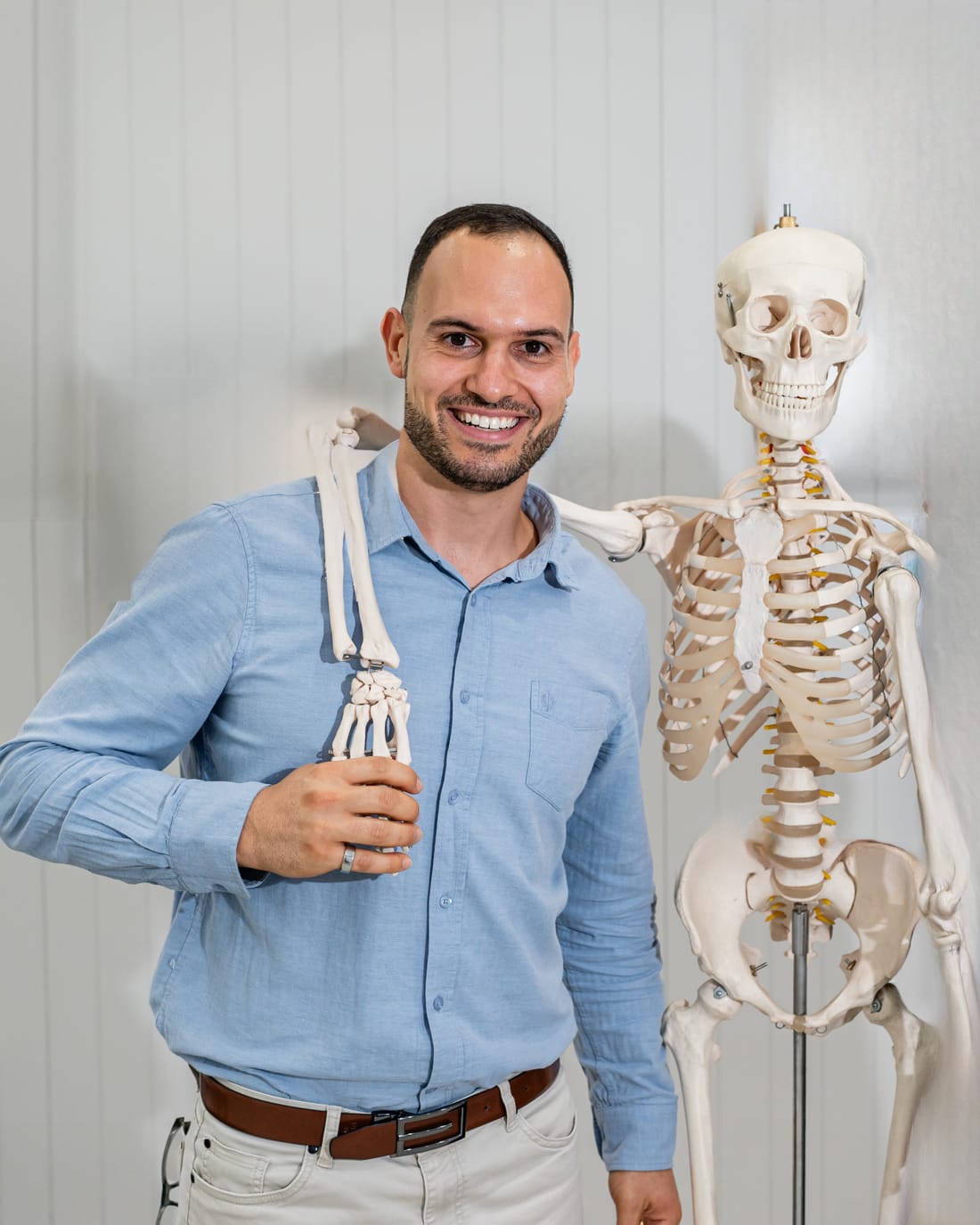 Dr Josh smiling beside the clinic’s model skeleton
